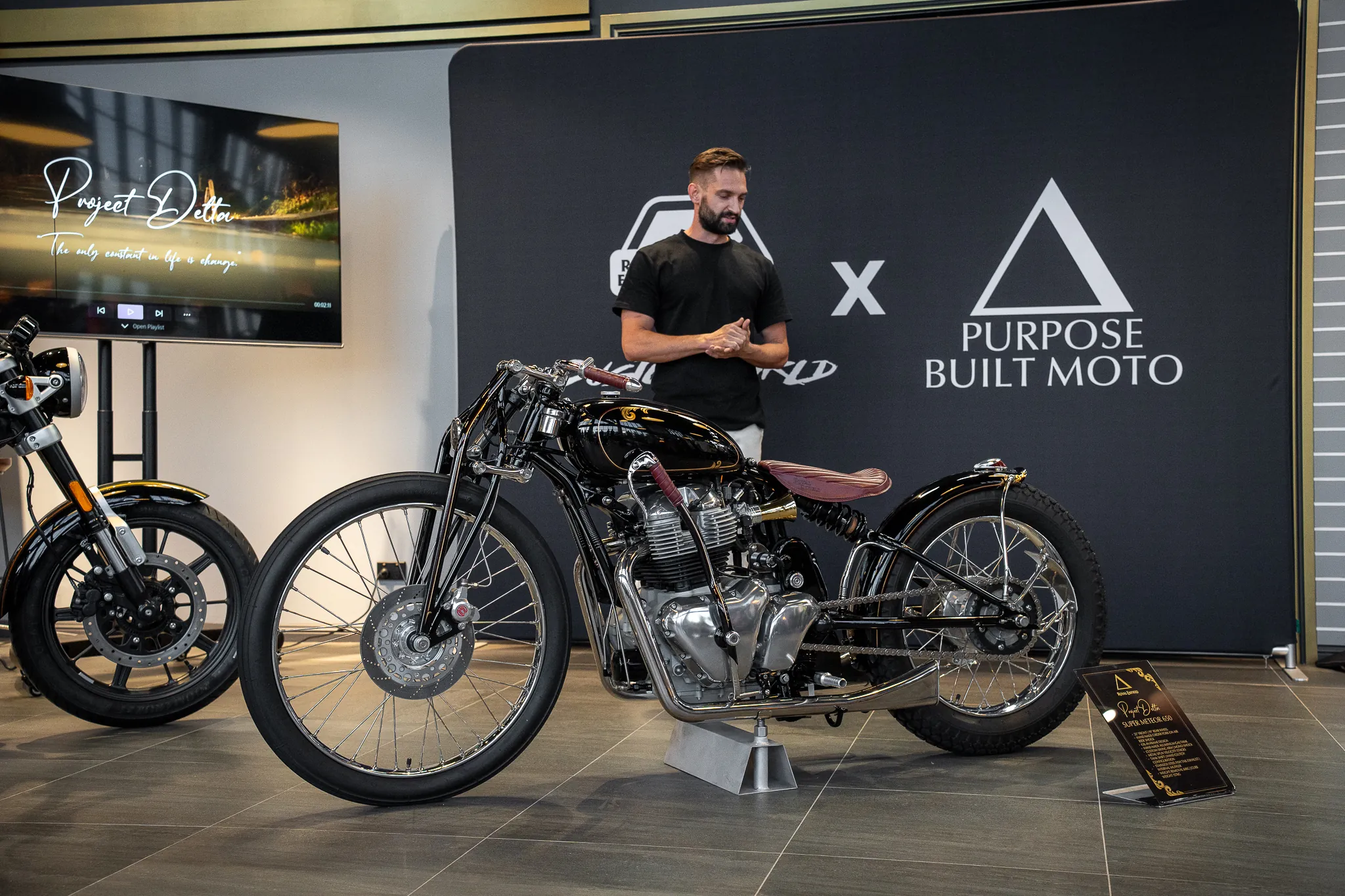 A custom motorcycle on display, with a man standing behind it