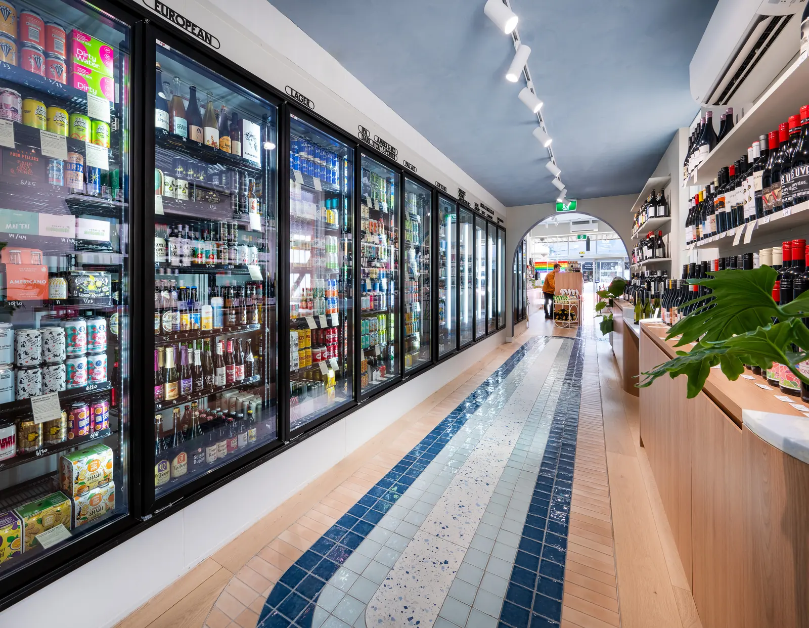 A long run of fridges beside the tiled path through the store