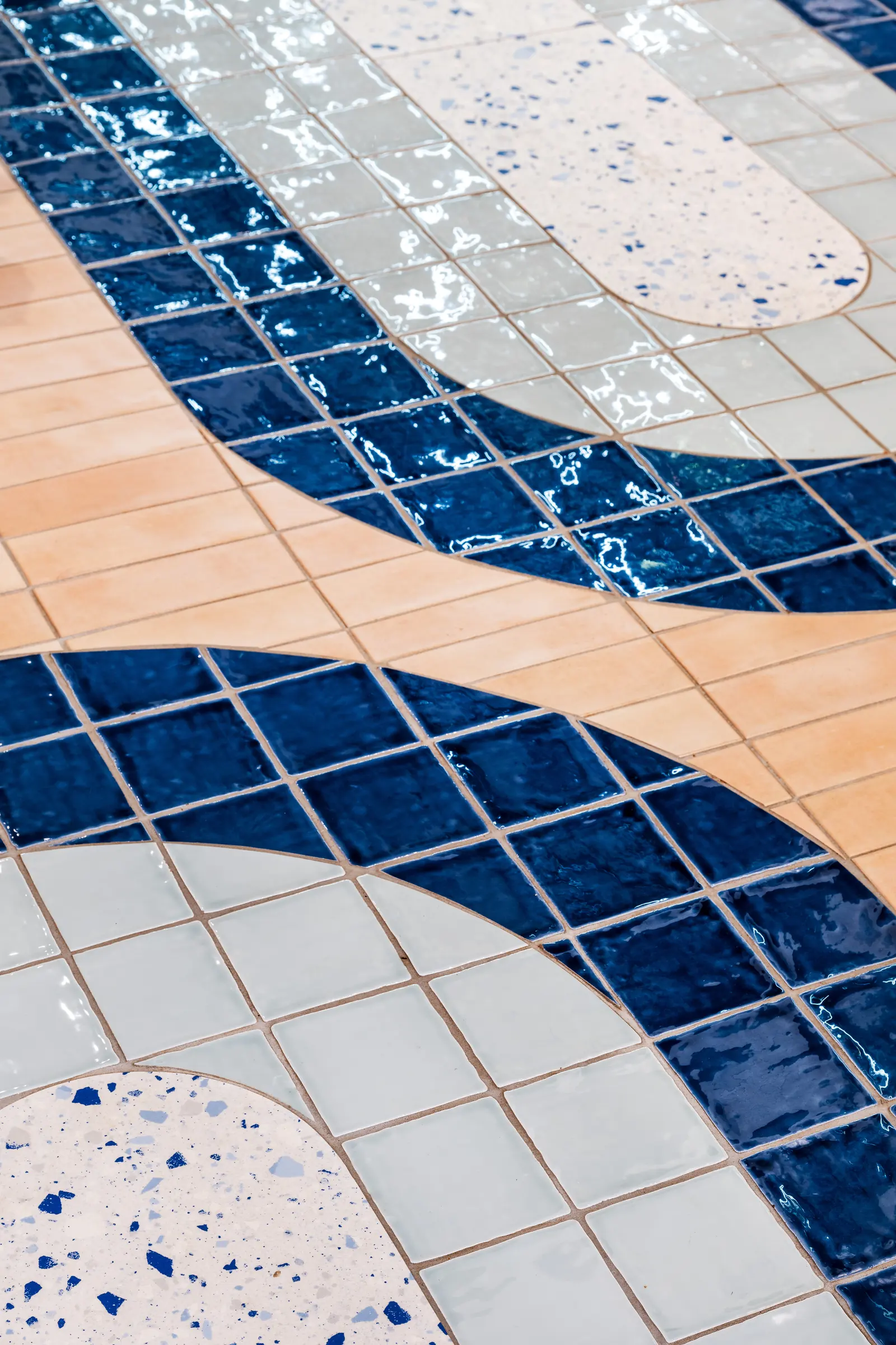 Blue and white glazed tiles meeting terrazzo in a curved floor pattern