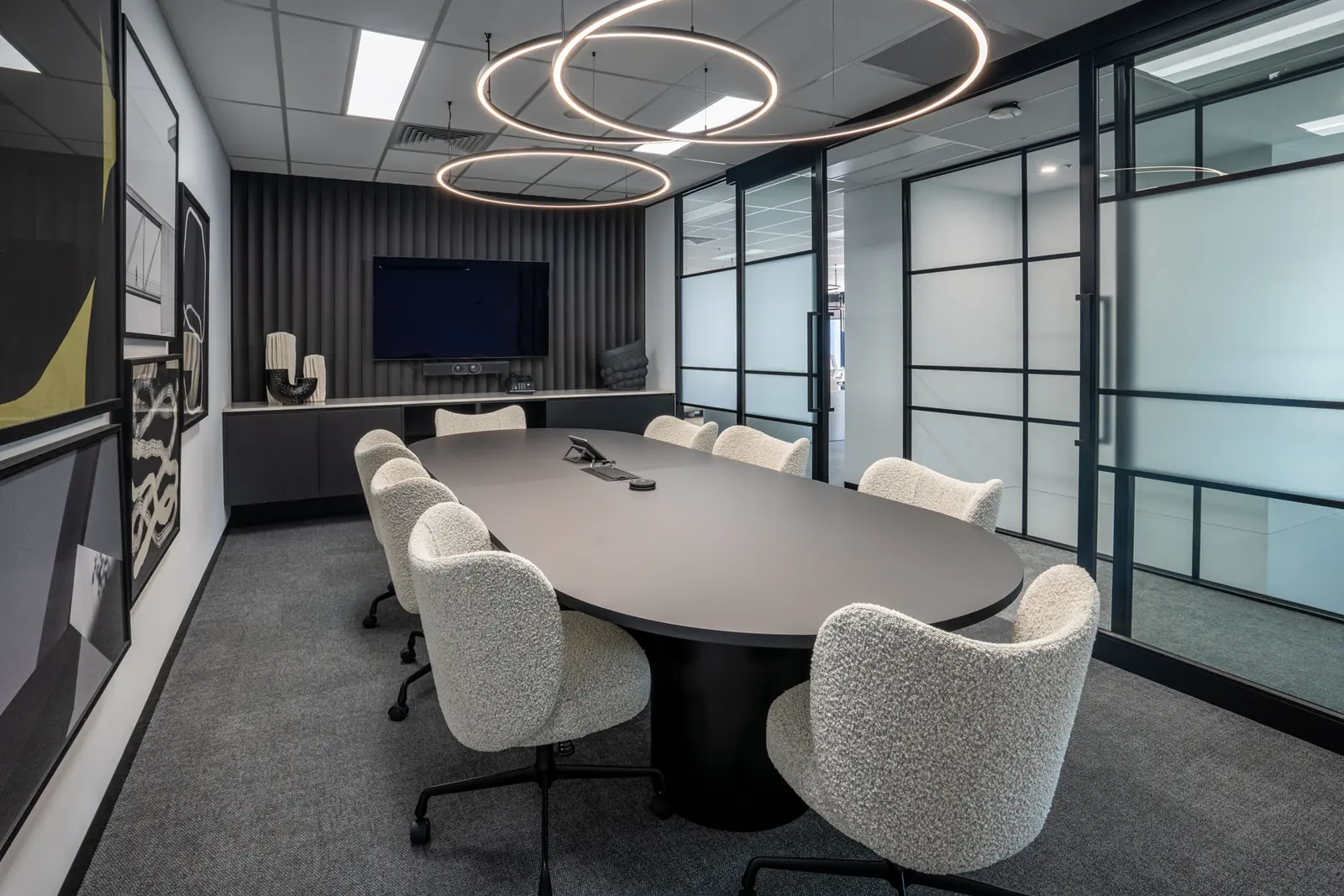 Boardroom with an oval table, upholstered chairs and circular pendant lights