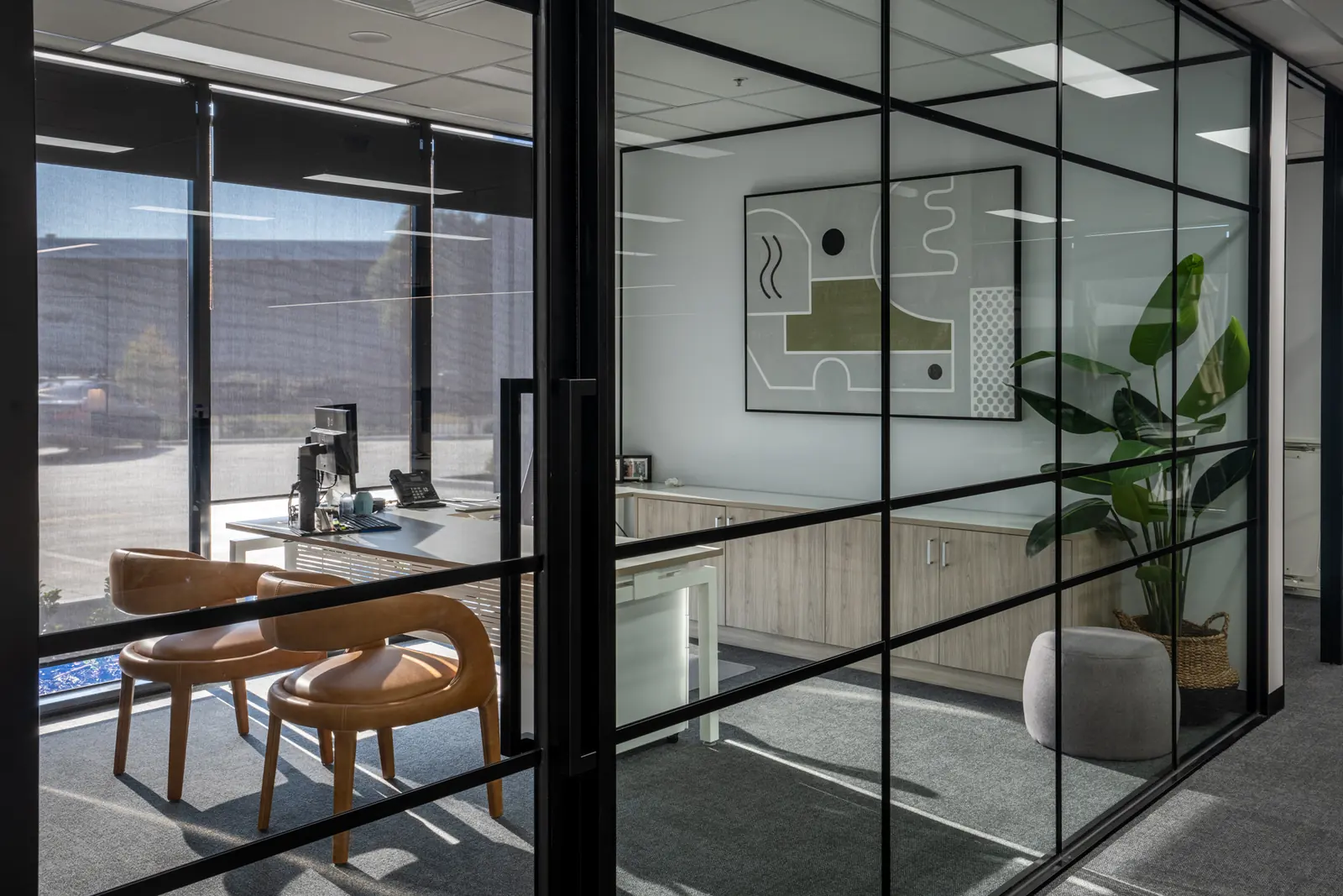 Black-framed glazed offices with timber desks and planting