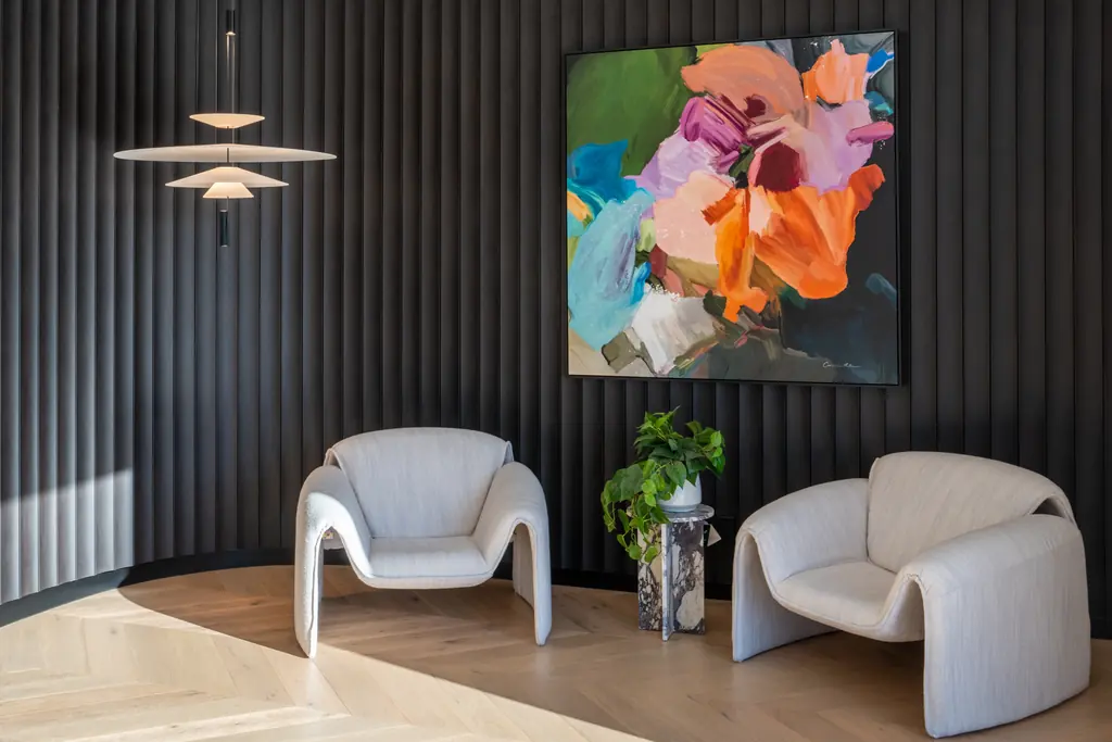 Reception with charcoal fluted wall panelling, two curved lounge chairs and a pendant light