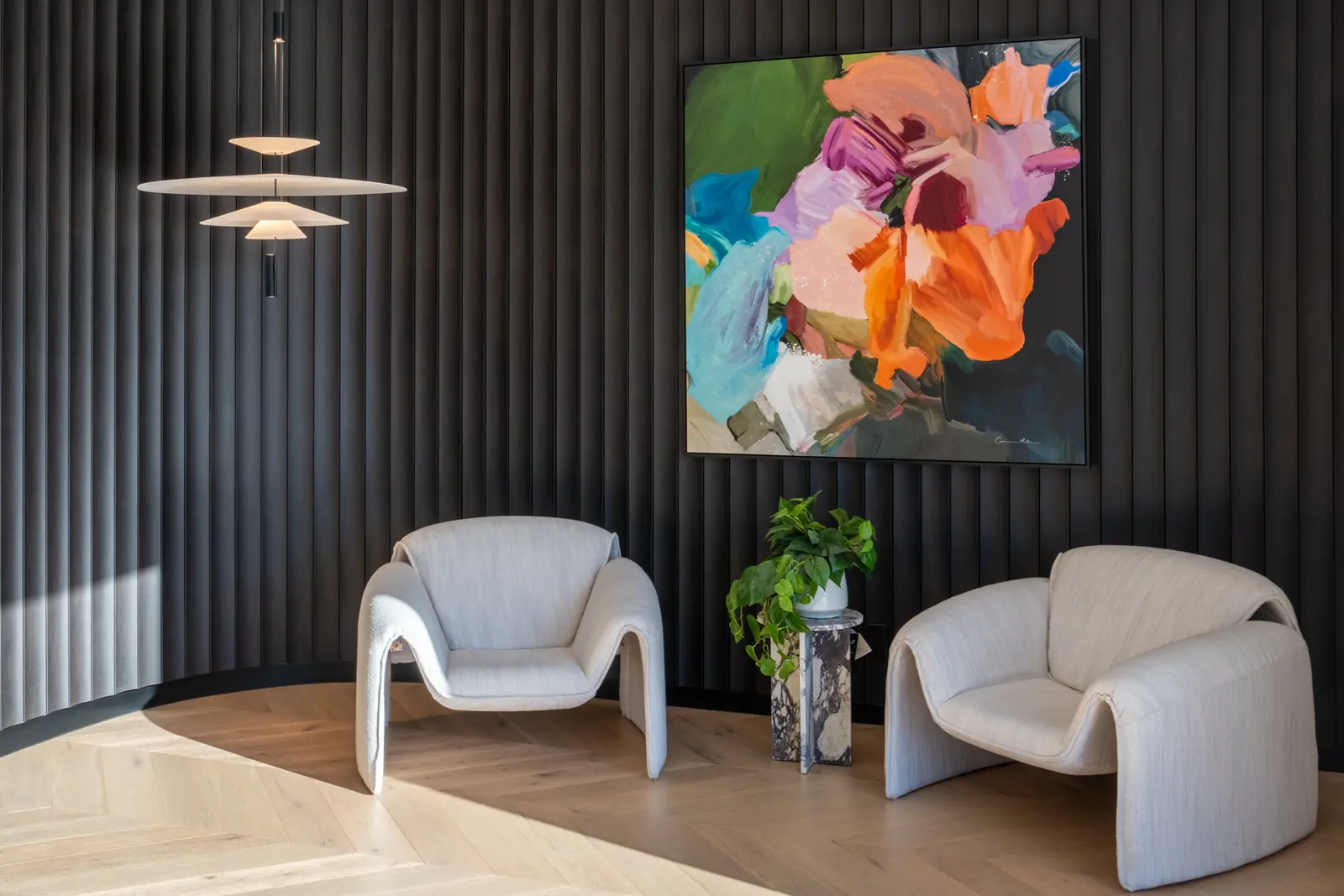 Reception with charcoal fluted wall panelling, two curved lounge chairs and a pendant light