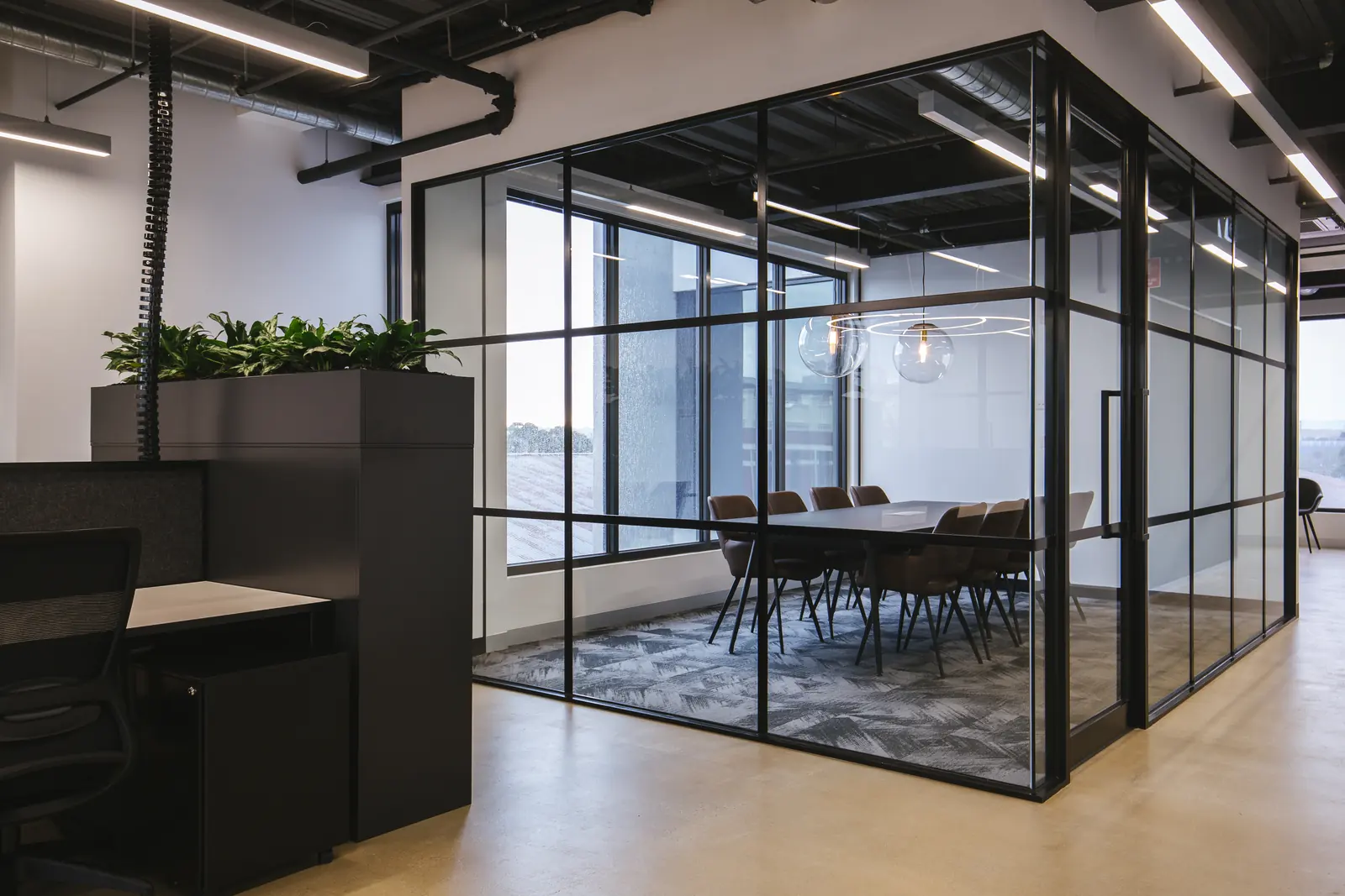 Black-framed glass meeting room beside the workstations