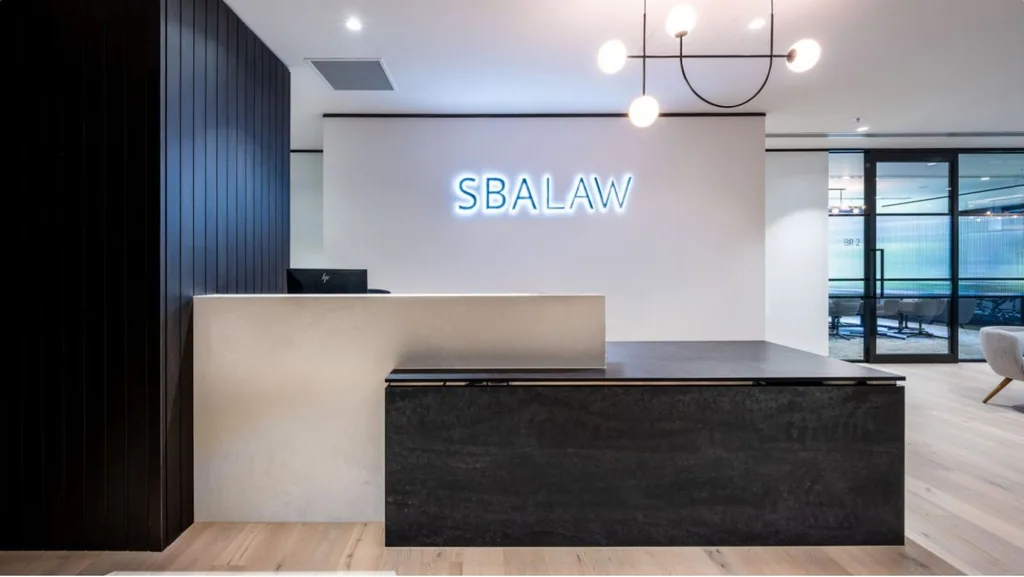 Reception with a dark stone counter, backlit signage and black vertical panelling