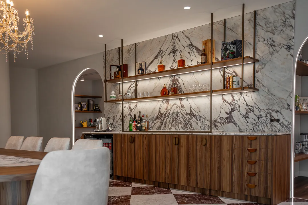 Dark timber joinery run under suspended shelving against a veined marble wall