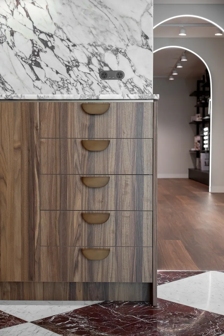 Timber drawer unit with brass half-moon pulls under a marble top